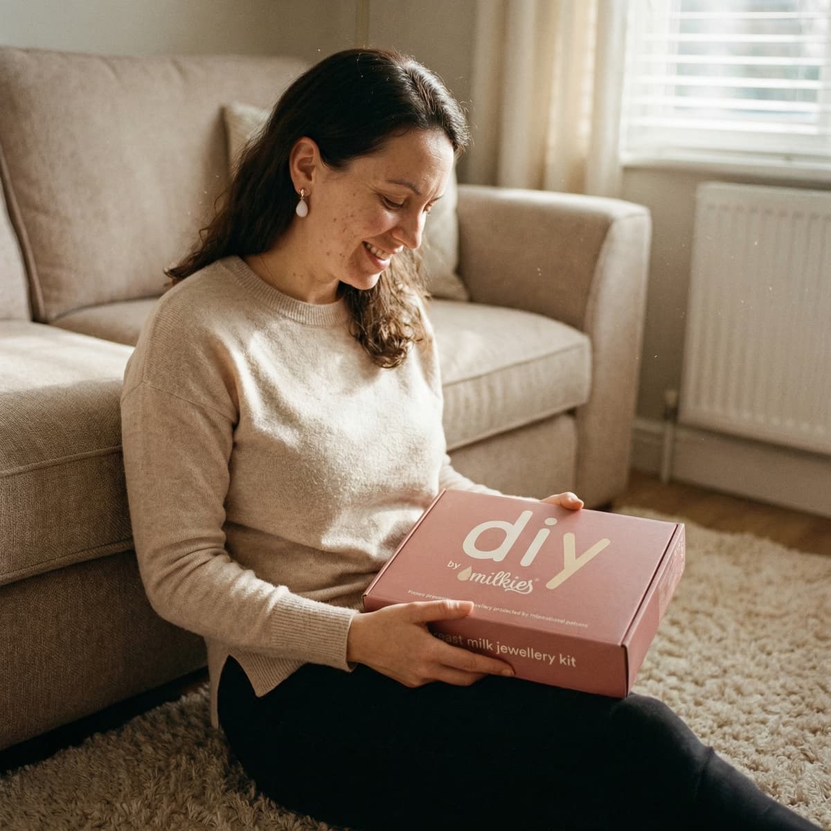 Smiling mom at home opening a DIY by MILKIES jewelry box, showing why a breastmilk earring diy kit is an easy, private way to create a meaningful keepsake