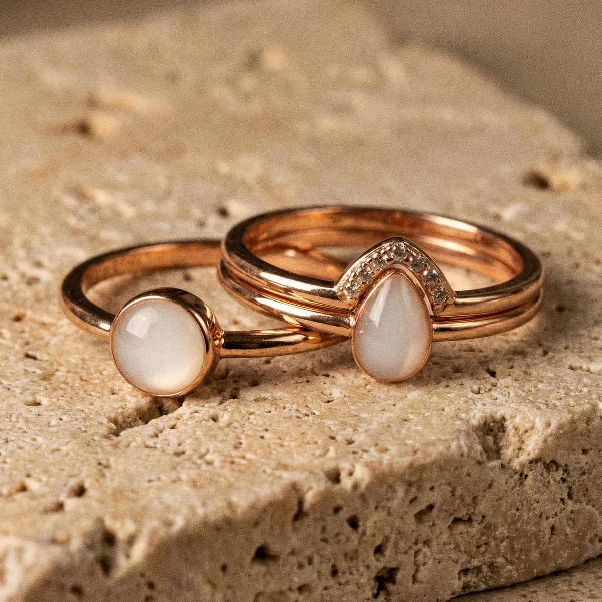Rose gold rings with milky white resin stones, a finished keepsake made using a breastmilk ring kit, photographed on a textured stone surface.