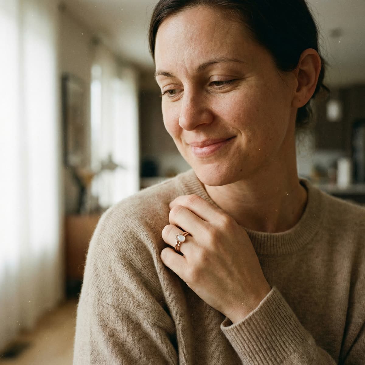 Smiling mother in a cozy home wearing a keepsake ring made with a breastmilk ring kit, highlighting why creating meaningful DIY jewelry at home is a special choice.