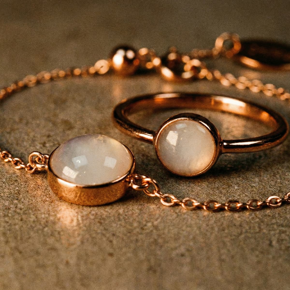 Rose gold jewelry set with a milky white resin stone diy breastmilk bracelet and matching ring displayed on a textured surface