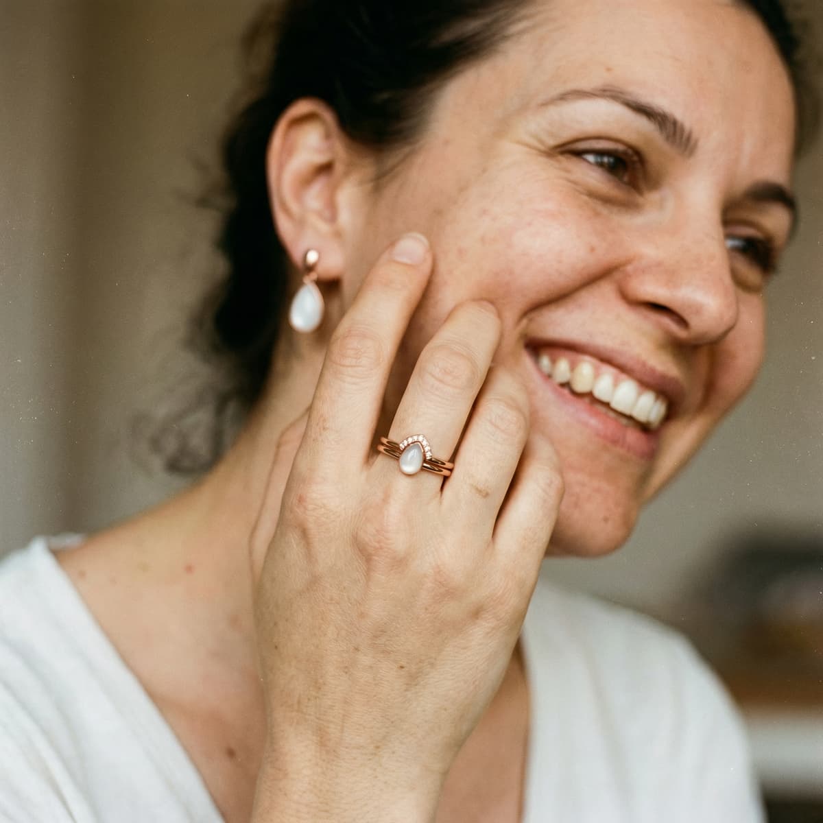 Smiling mom wearing a rose-gold keepsake ring with a milky-white stone, showing why a diy breastmilk ring kit is a meaningful at-home way to create personal breastmilk jewelry.