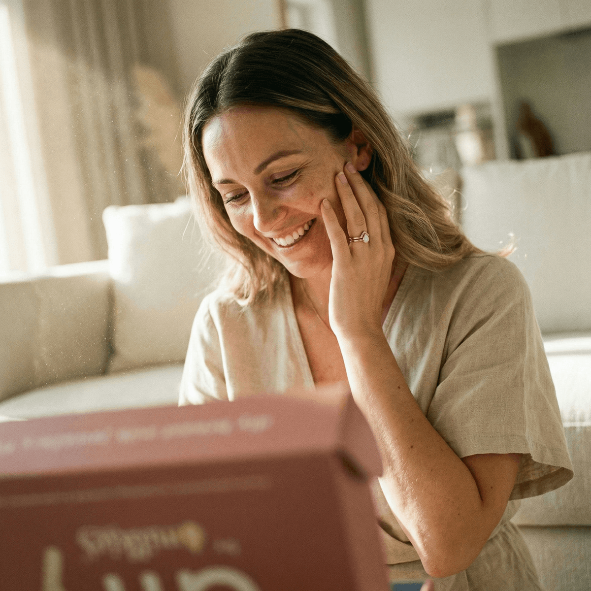 Smiling mom at home admiring a keepsake ring and DIY kit box, showing why diy breastmilk rings are a meaningful, private way to create a breastmilk jewelry keepsake yourself.
