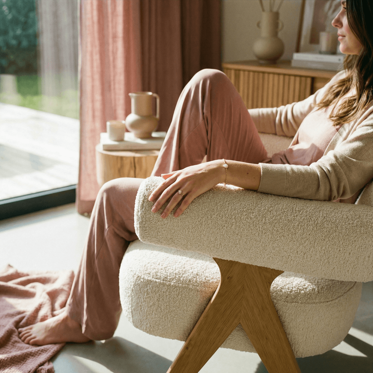 Mother relaxing in a cozy armchair wearing delicate breastmilk keepsake jewelry, a calm at-home moment associated with drying up milk and preserving breastfeeding memories.