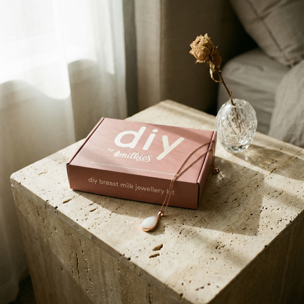 Rose-gold breast milk jewelry kit box by DIY by MILKIES with pendant necklace on stone table by a sunlit window, a meaningful push present keepsake for new moms