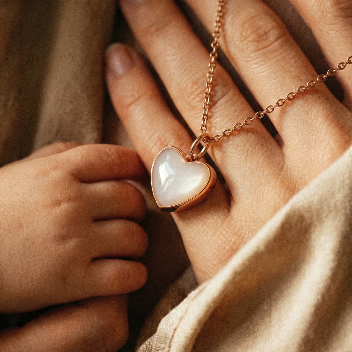 Mother and baby hands holding a rose-gold heart pendant on a delicate chain, made with a diy breastmilk necklace kit keepsake resin jewelry set.